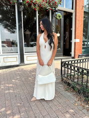 Woman wearing natural colored maxi dress with halter keyhole cutout neckline and tie back.