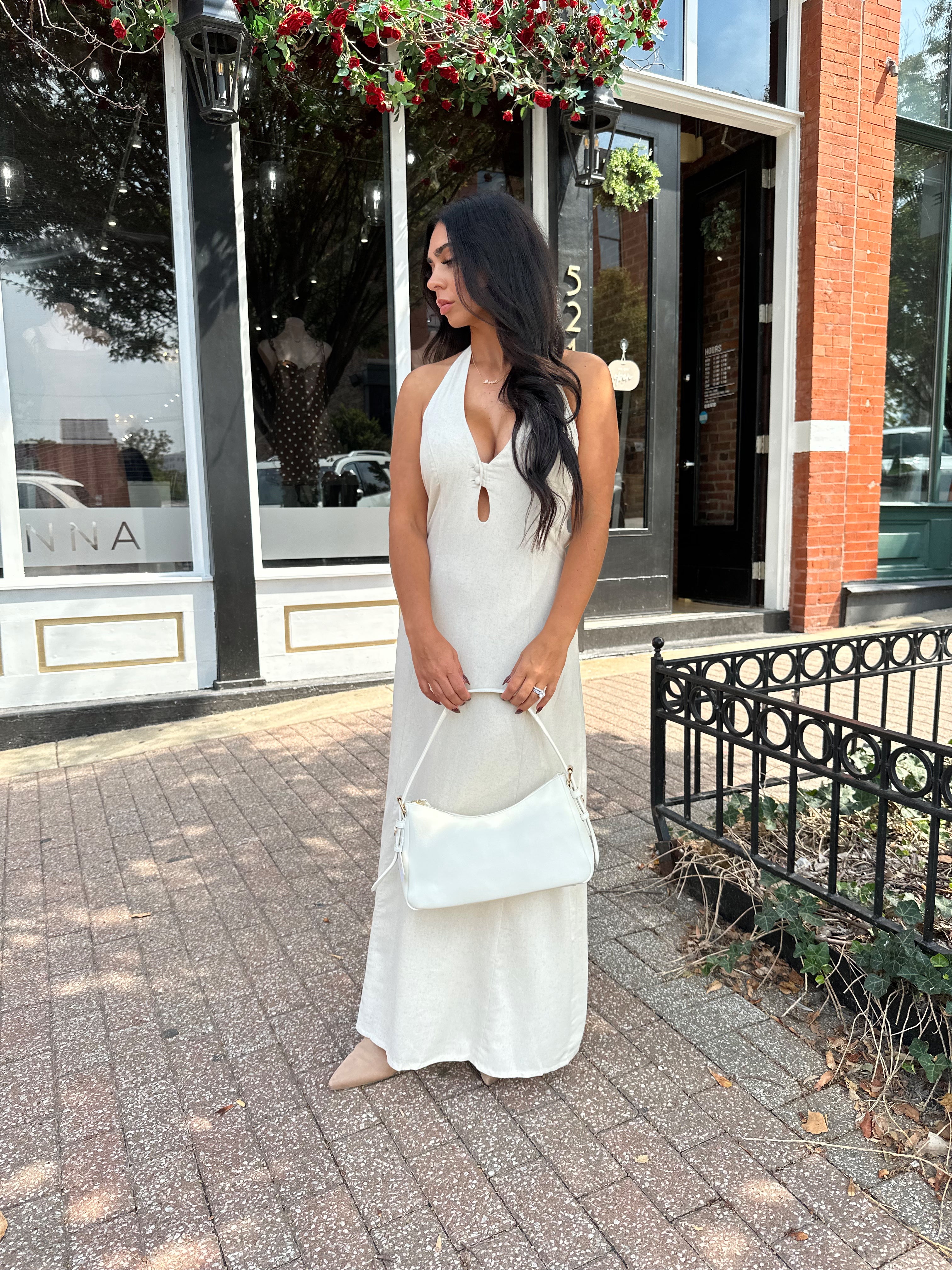 Woman wearing natural colored maxi dress with halter keyhole cutout neckline and tie back.