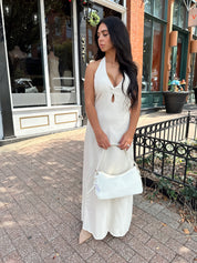 Woman wearing natural colored maxi dress with halter keyhole cutout neckline and tie back.