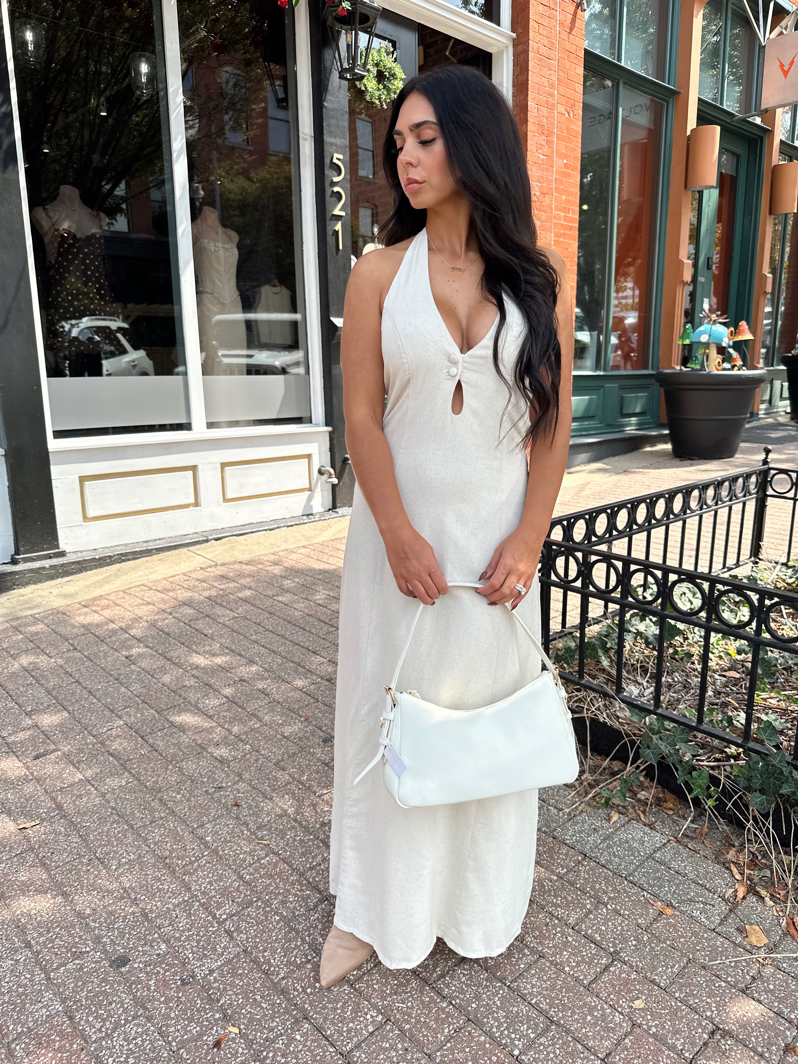 Woman wearing natural colored maxi dress with halter keyhole cutout neckline and tie back.