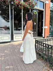 Woman wearing natural colored maxi dress with halter keyhole cutout neckline and tie back.