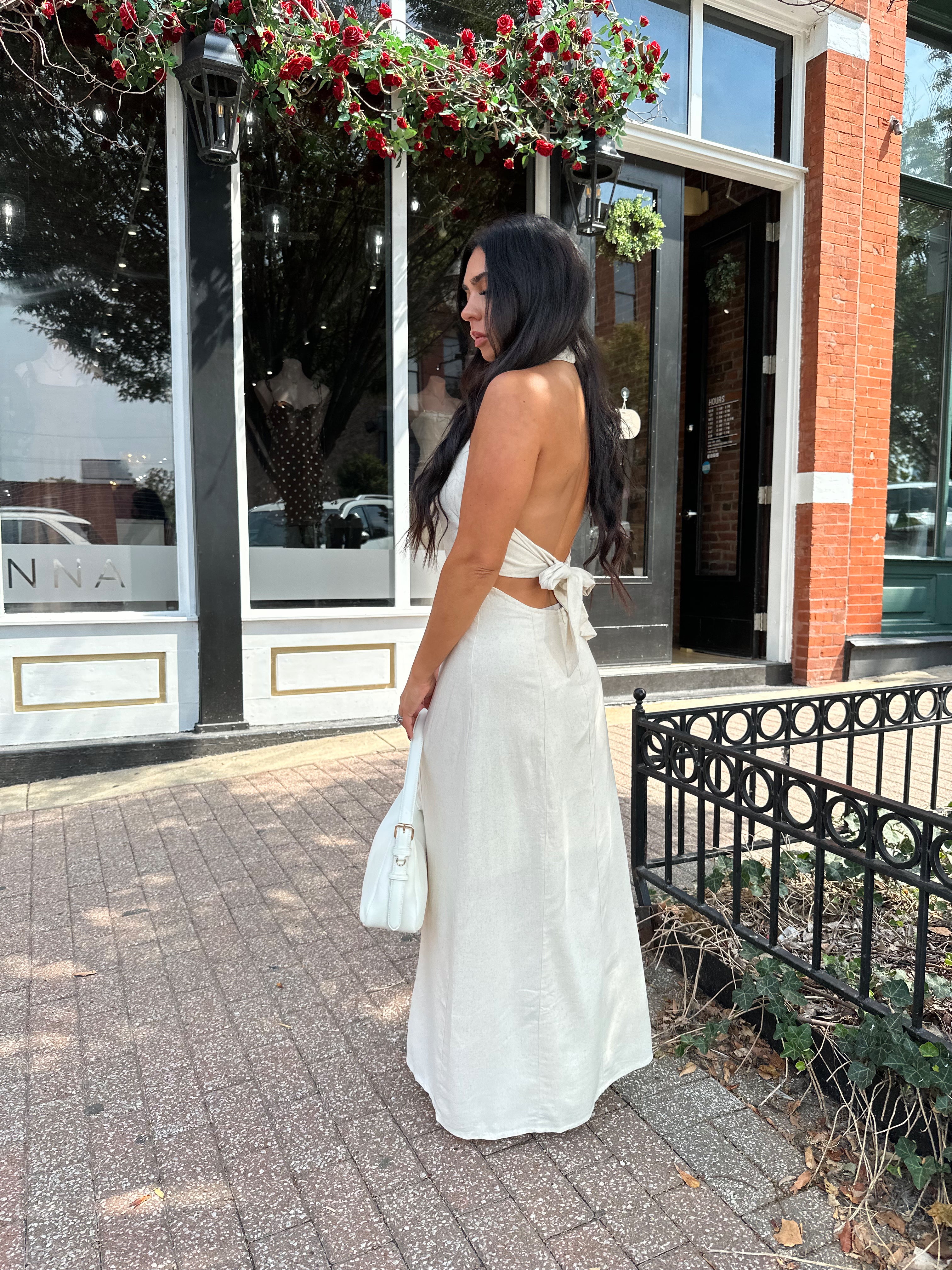 Woman wearing natural colored maxi dress with halter keyhole cutout neckline and tie back.