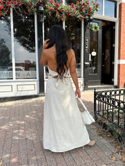 Woman wearing natural colored maxi dress with halter keyhole cutout neckline and tie back.