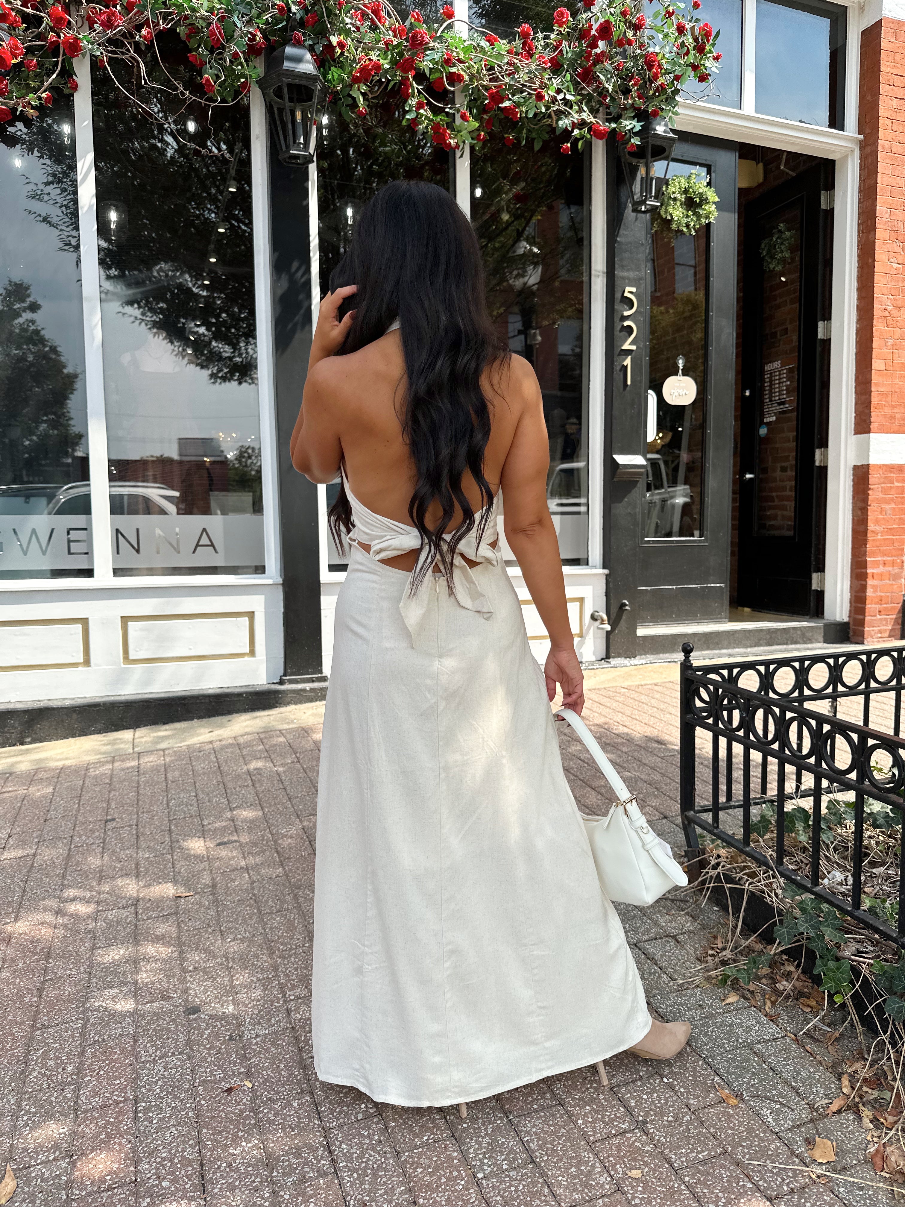 Woman wearing natural colored maxi dress with halter keyhole cutout neckline and tie back.