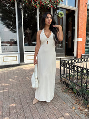 Woman wearing natural colored maxi dress with halter keyhole cutout neckline and tie back.