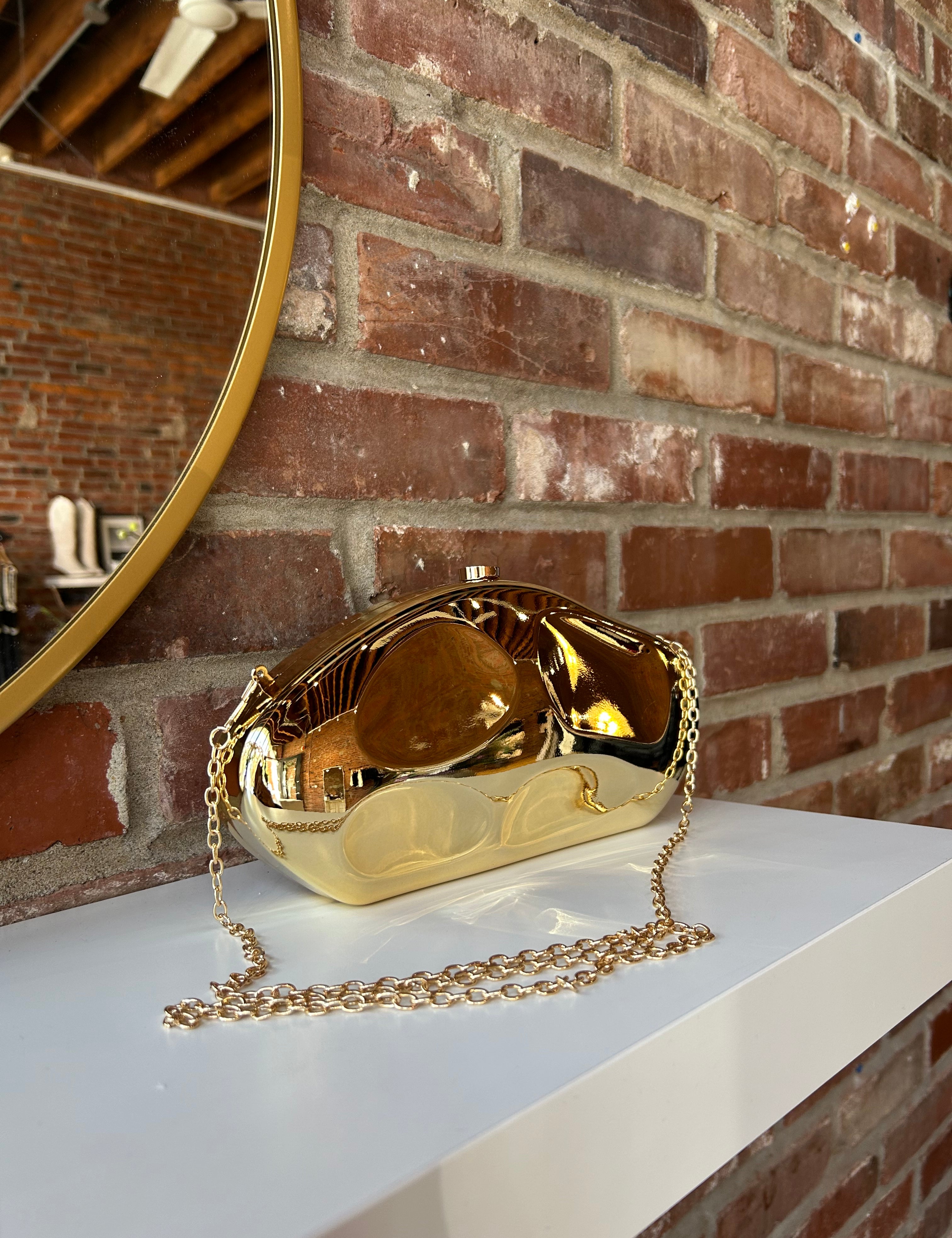 Gold hardshell clutch bag with detachable chain. 