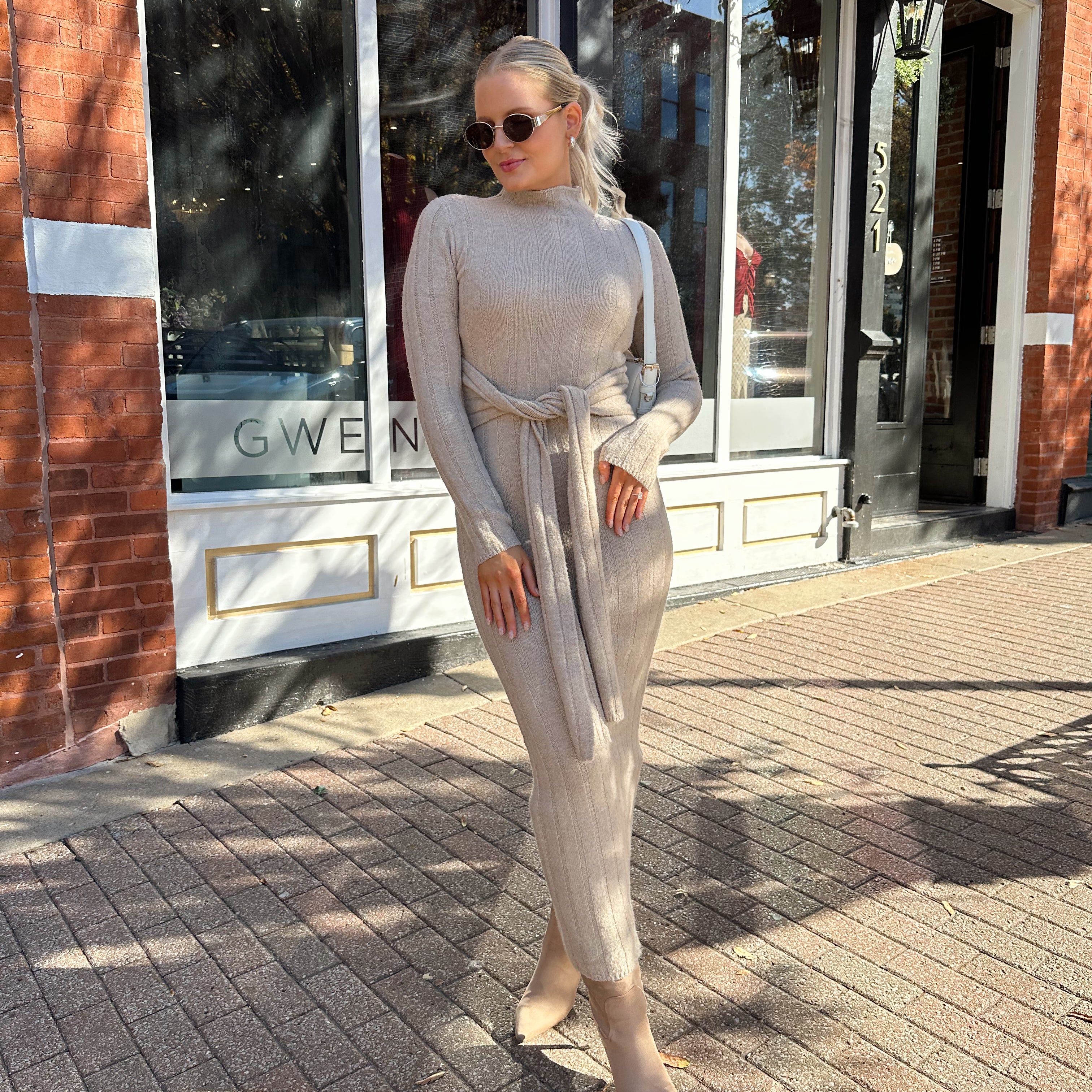 Woman wearing mocha long sleeve knit sweater dress with tie front detail. 