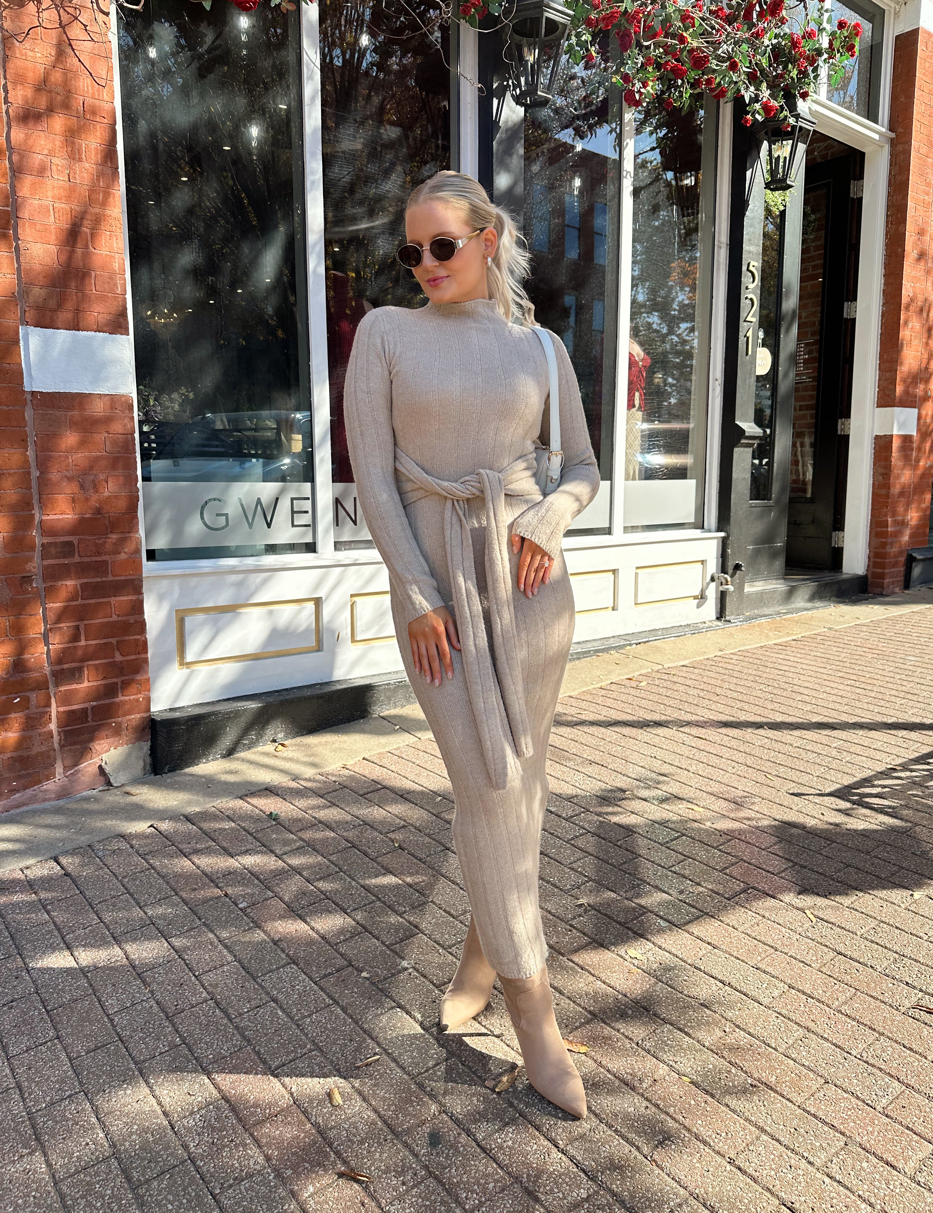 Woman wearing mocha long sleeve knit sweater dress with tie front detail. 