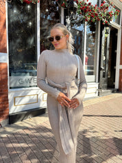 Woman wearing mocha long sleeve knit sweater dress with tie front detail. 