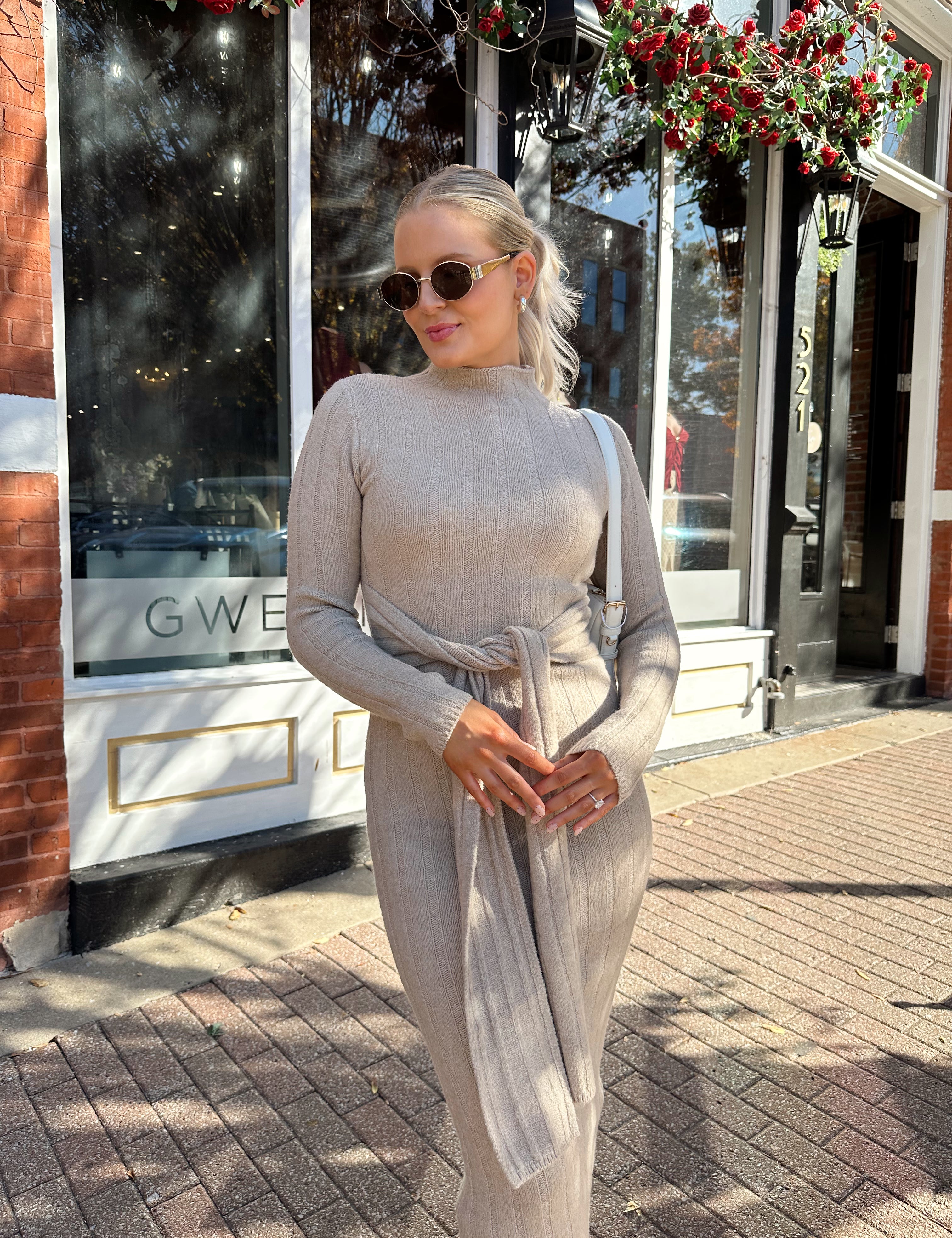 Woman wearing mocha long sleeve knit sweater dress with tie front detail. 