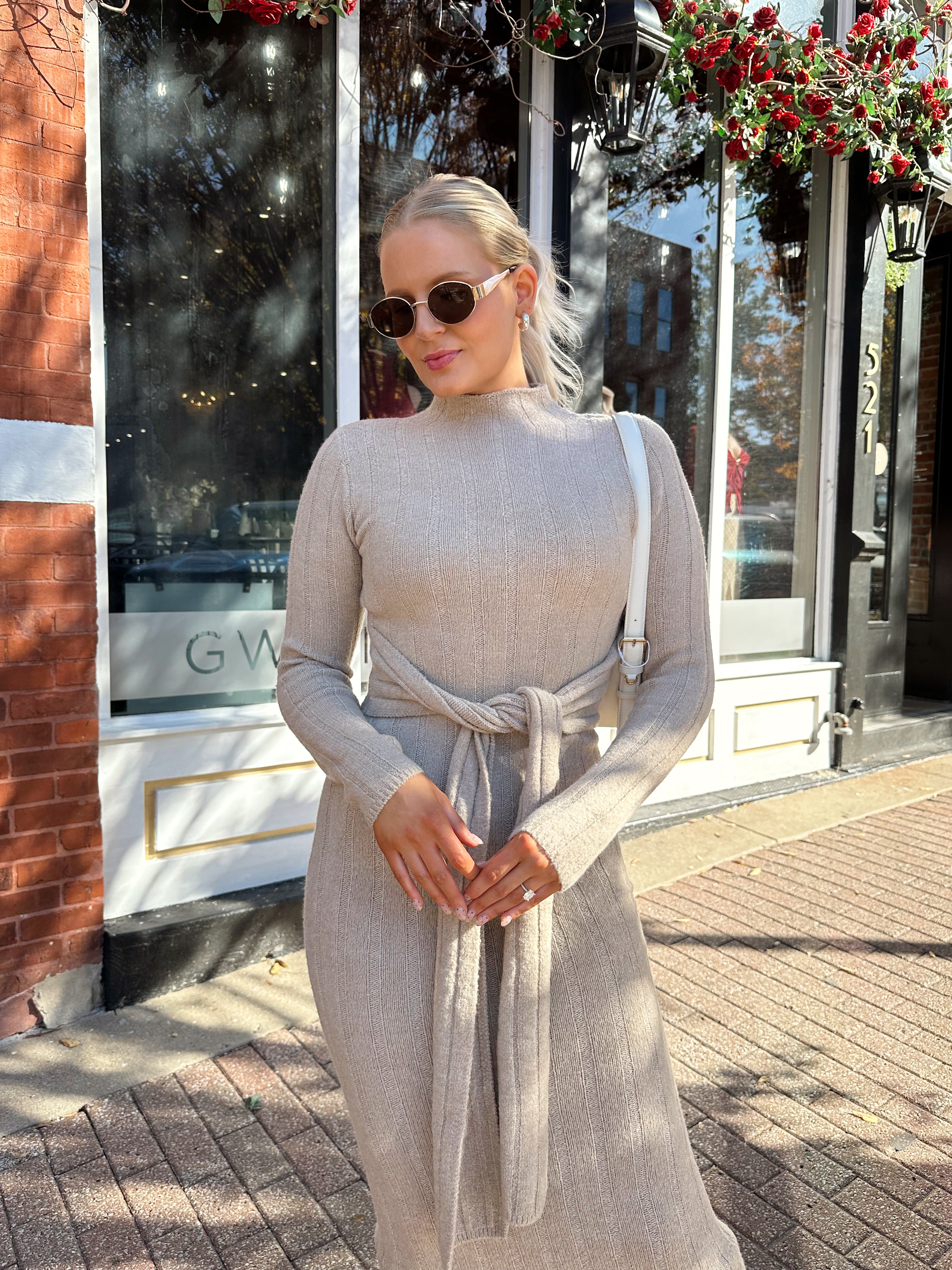 Woman wearing mocha long sleeve knit sweater dress with tie front detail. 