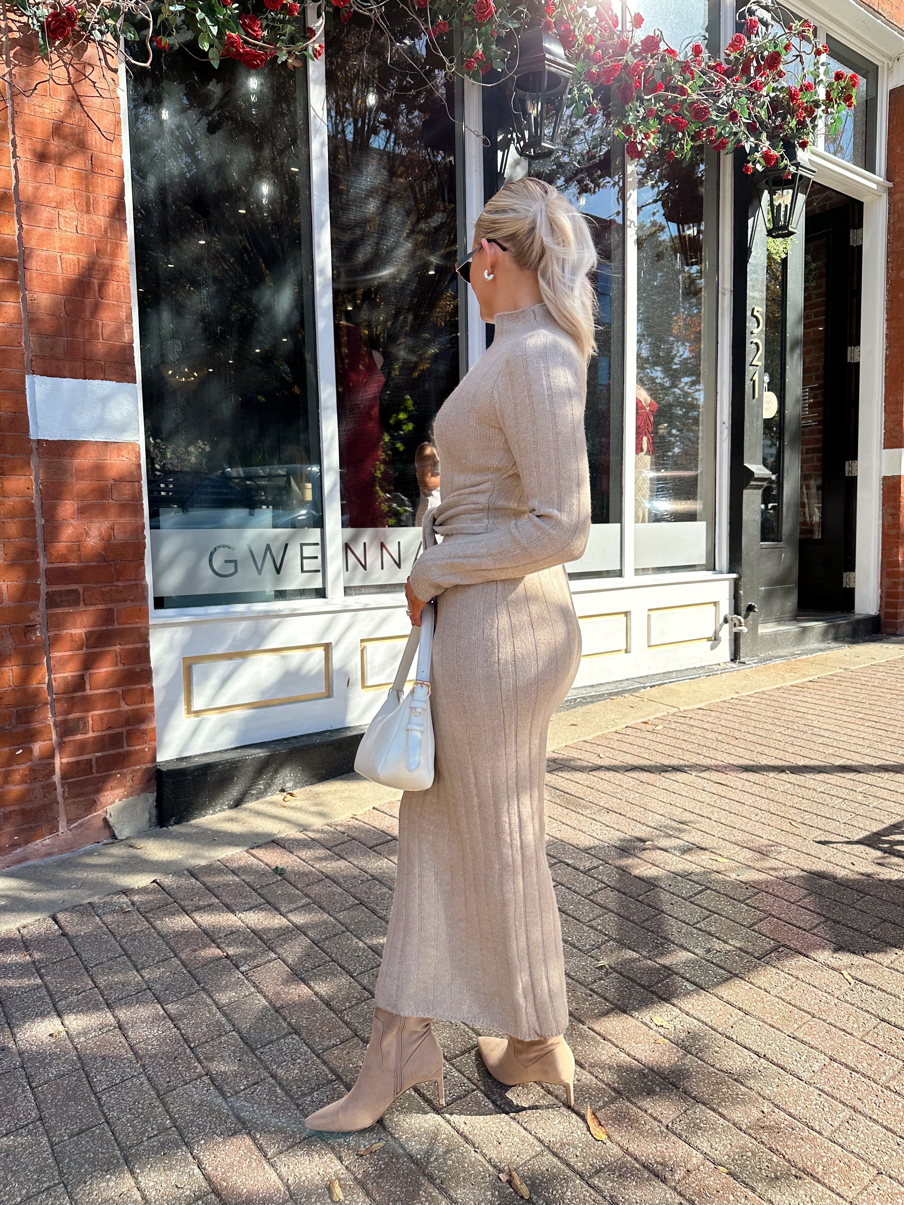 Woman wearing mocha long sleeve knit sweater dress with tie front detail. 