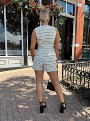 Woman wearing white and black striped tweed two piece set with high waisted short and button down top.