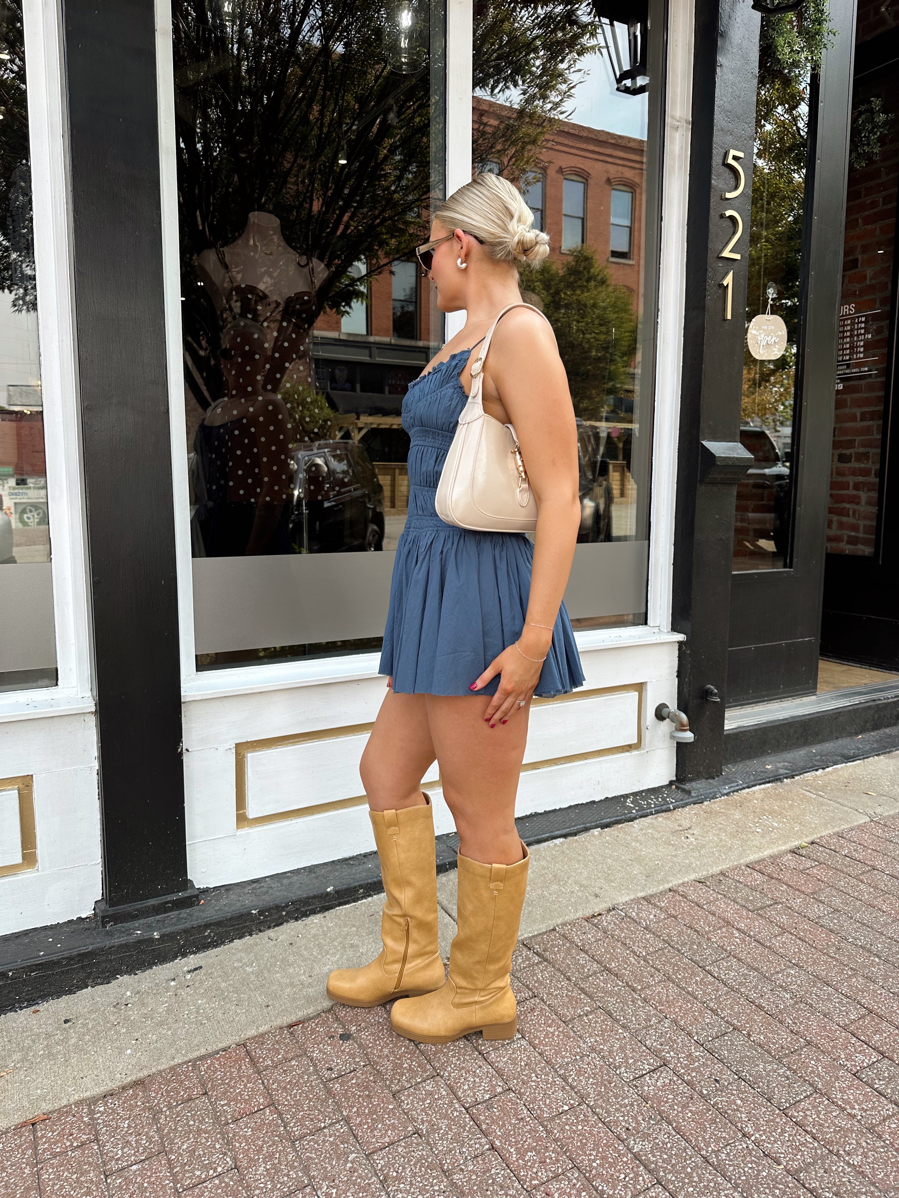 Woman wearing dusty blue smocked mini dress with built in shorts and adjustable straps.