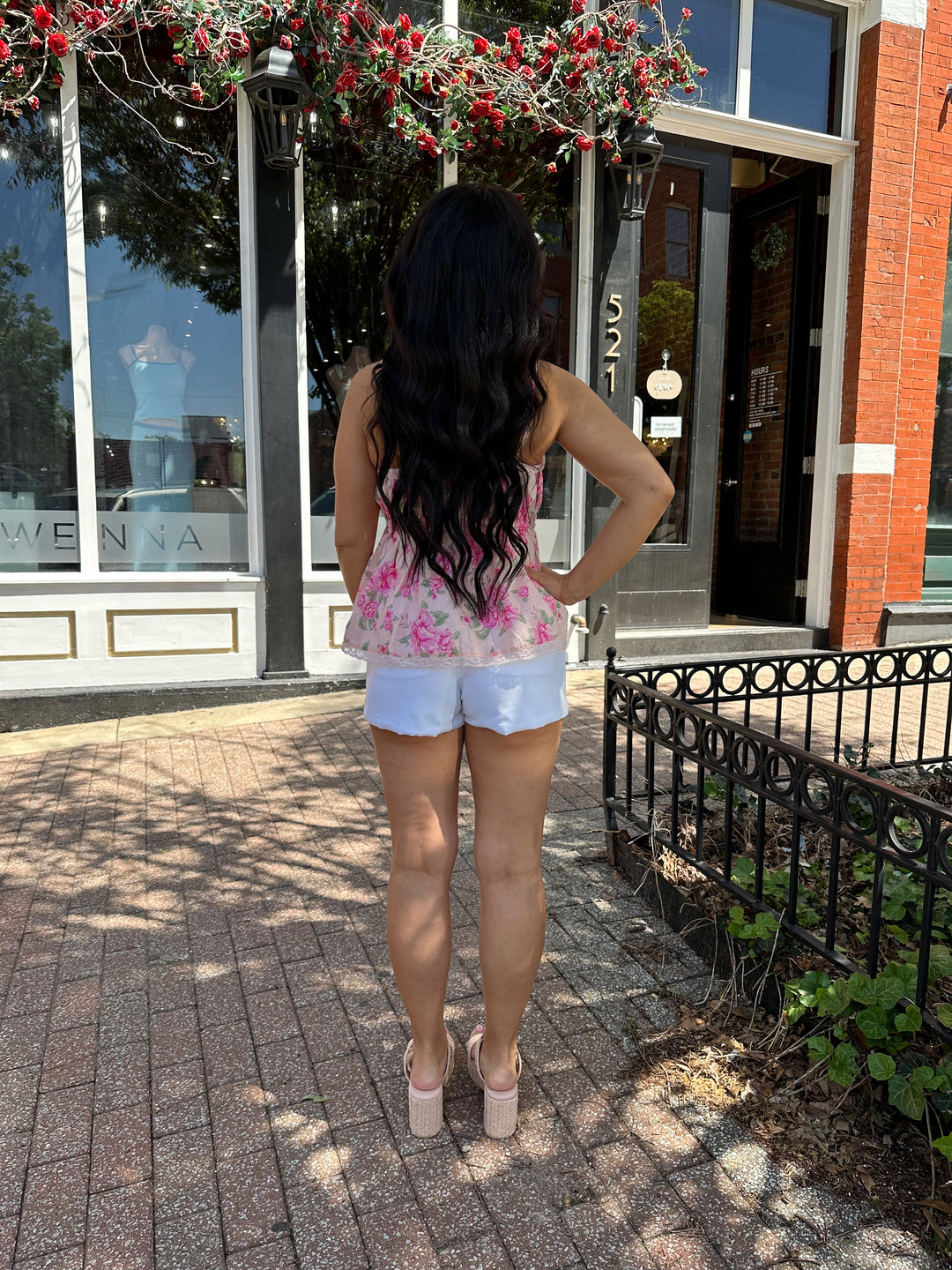 Woman wearing pink floral babydoll tank top with white micro shorts. 