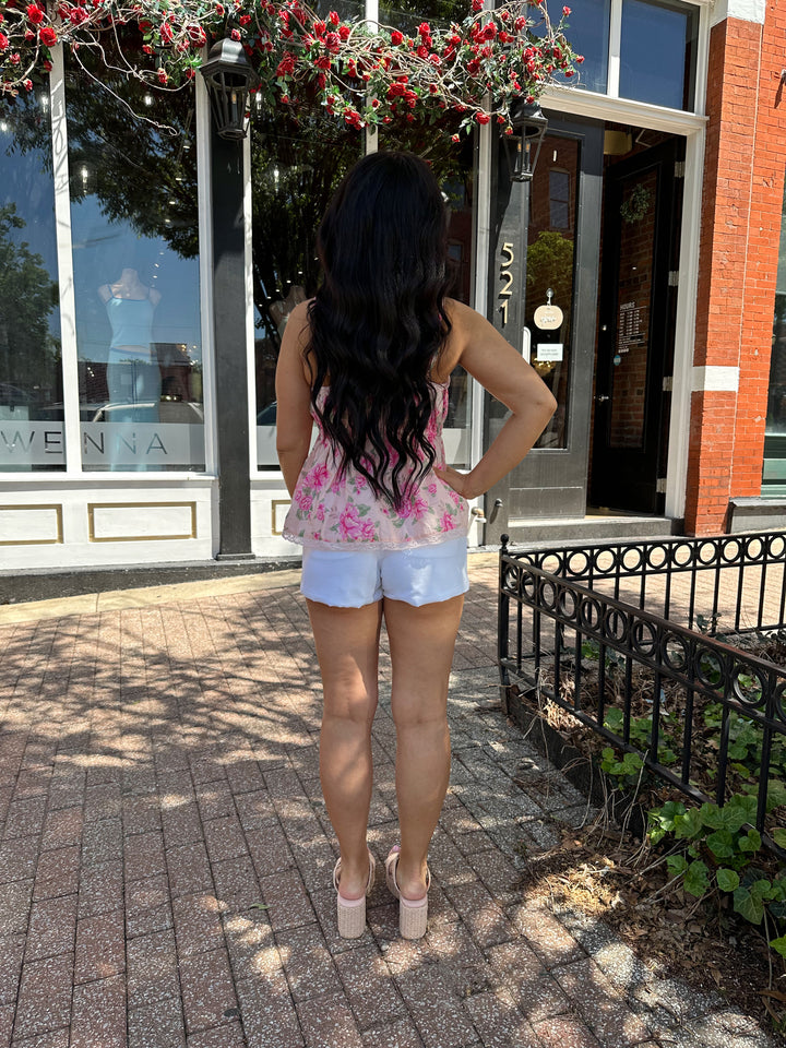Woman wearing pink floral babydoll tank top with white micro shorts. 