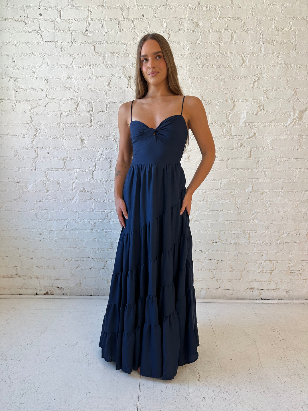 Woman wearing navy blue tiered maxi dress with twisted sweetheart neckline and smocked back.