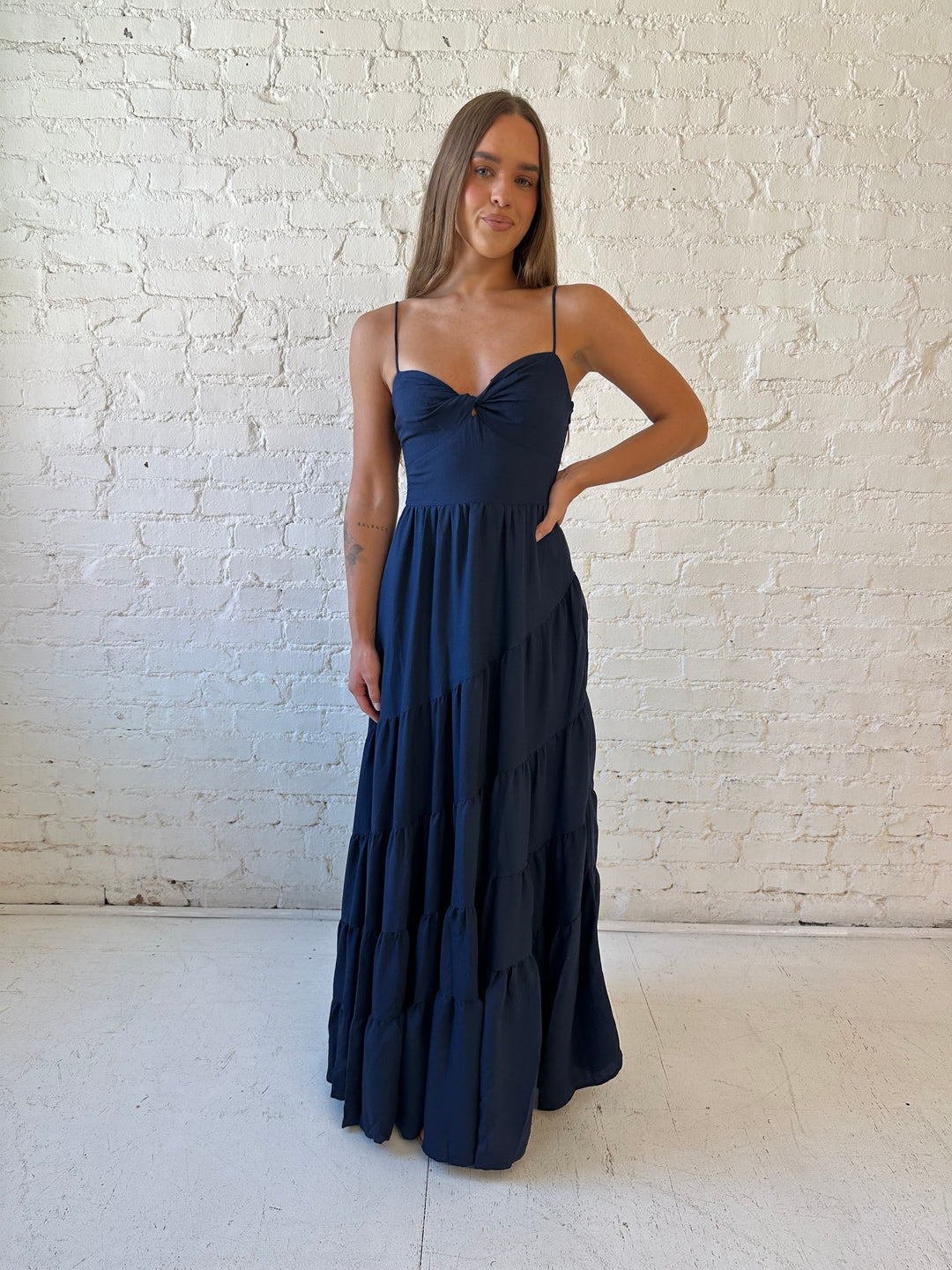 Woman wearing navy blue tiered maxi dress with twisted sweetheart neckline and smocked back.