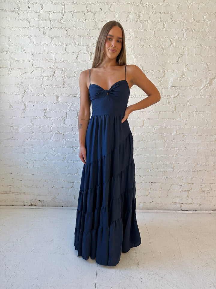Woman wearing navy blue tiered maxi dress with twisted sweetheart neckline and smocked back.