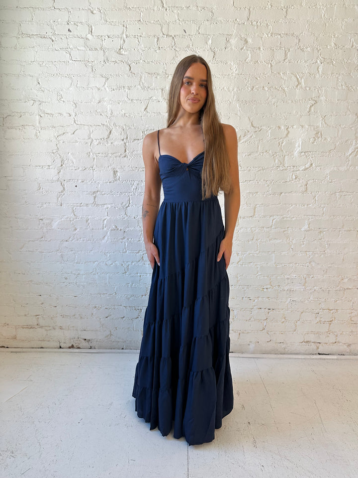 Woman wearing navy blue tiered maxi dress with twisted sweetheart neckline and smocked back.