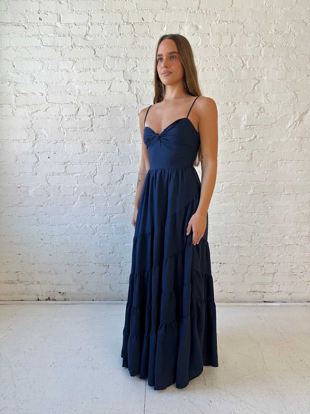Woman wearing navy blue tiered maxi dress with twisted sweetheart neckline and smocked back.