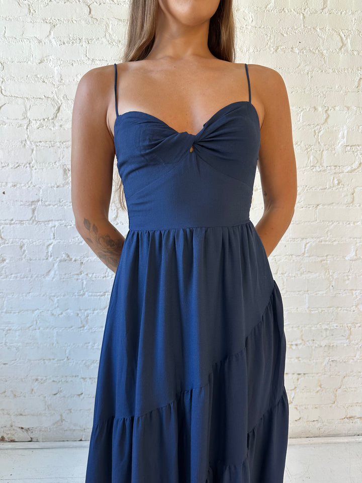 Woman wearing navy blue tiered maxi dress with twisted sweetheart neckline and smocked back.