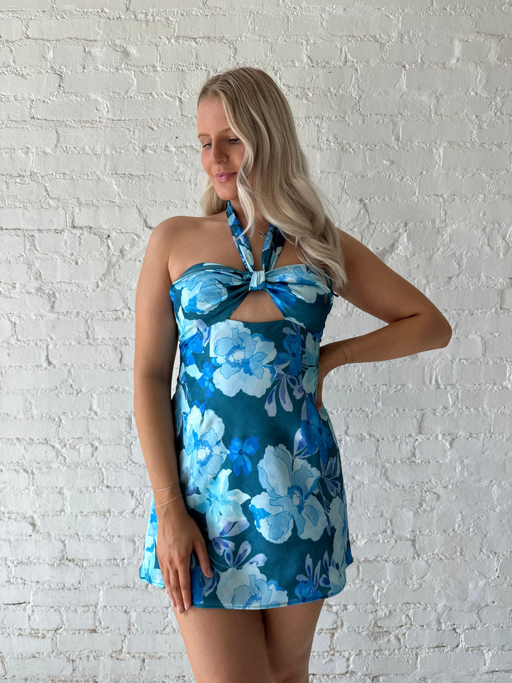 Woman wearing blue floral satin maxi dress with halter neckline, and keyhole cutout. 