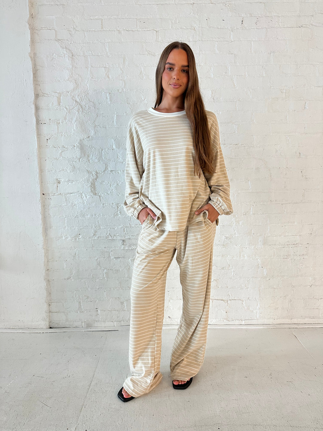 Woman wearing two piece tan striped long sleeve lounge set.
