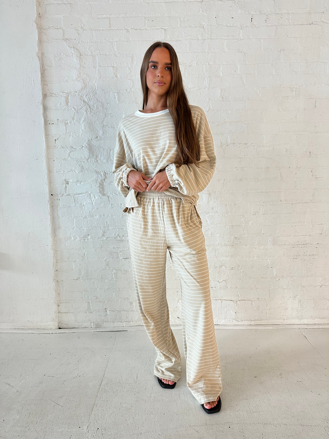 Woman wearing two piece tan striped long sleeve lounge set.