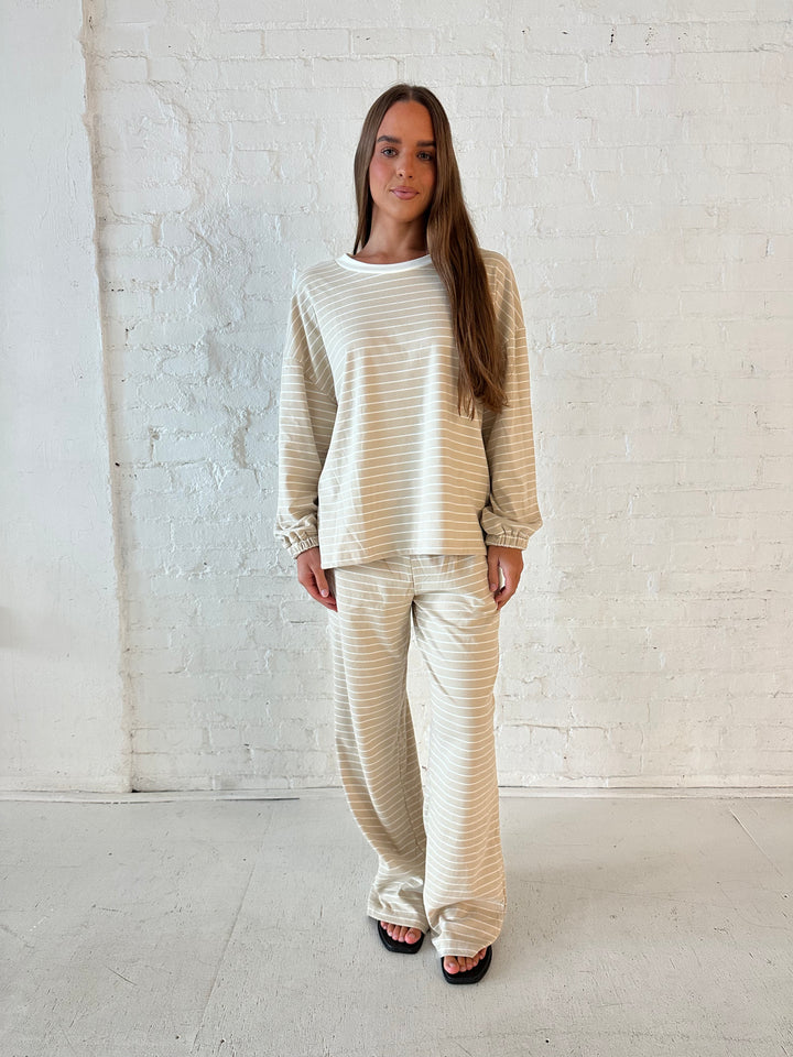 Woman wearing two piece tan striped long sleeve lounge set.