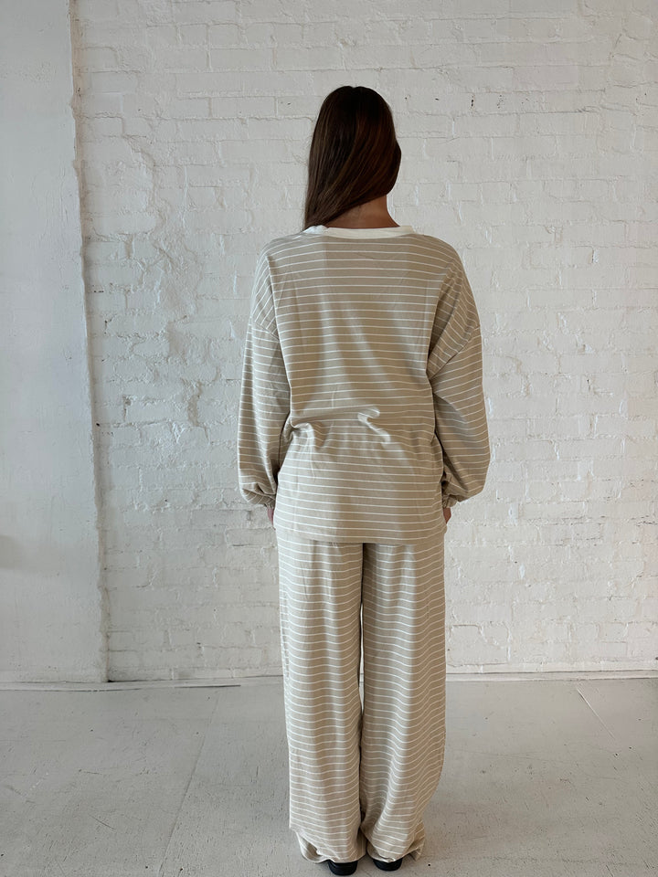 Woman wearing two piece tan striped long sleeve lounge set.