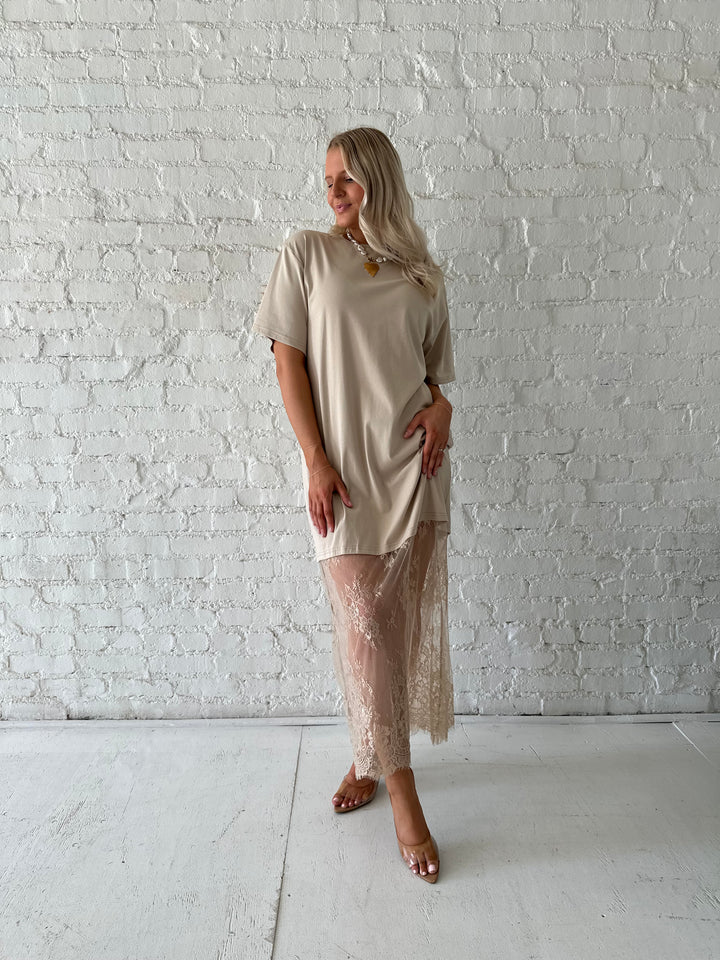 Woman wearing beige t-shirt dress with lace underlay, and oversized fit. 