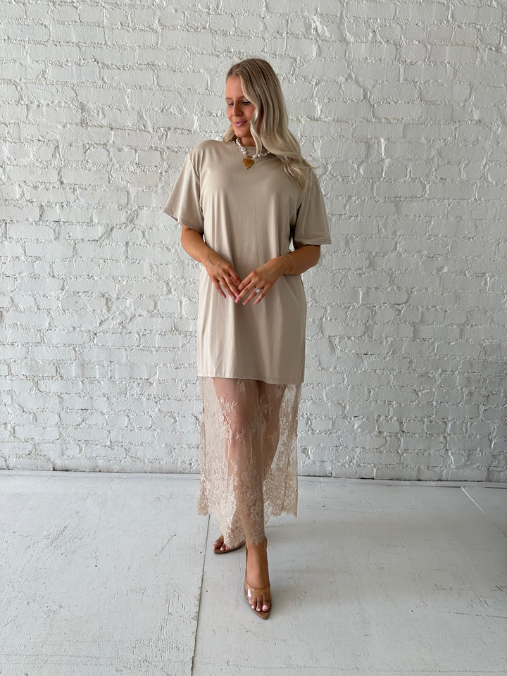 Woman wearing beige t-shirt dress with lace underlay, and oversized fit. 
