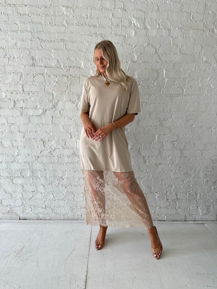 Woman wearing beige t-shirt dress with lace underlay, and oversized fit. 