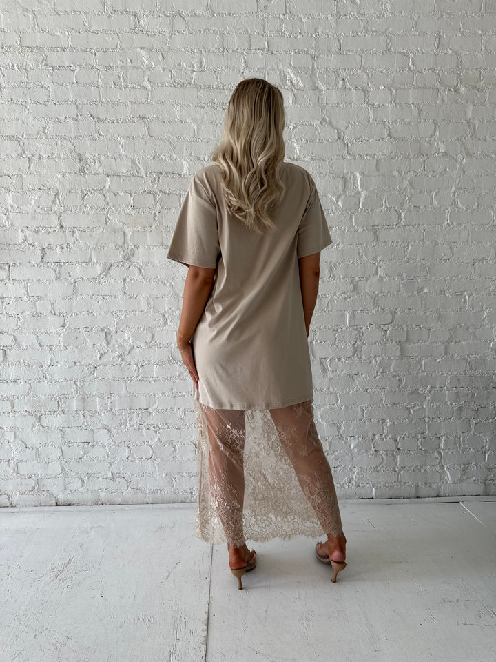 Woman wearing beige t-shirt dress with lace underlay, and oversized fit. 