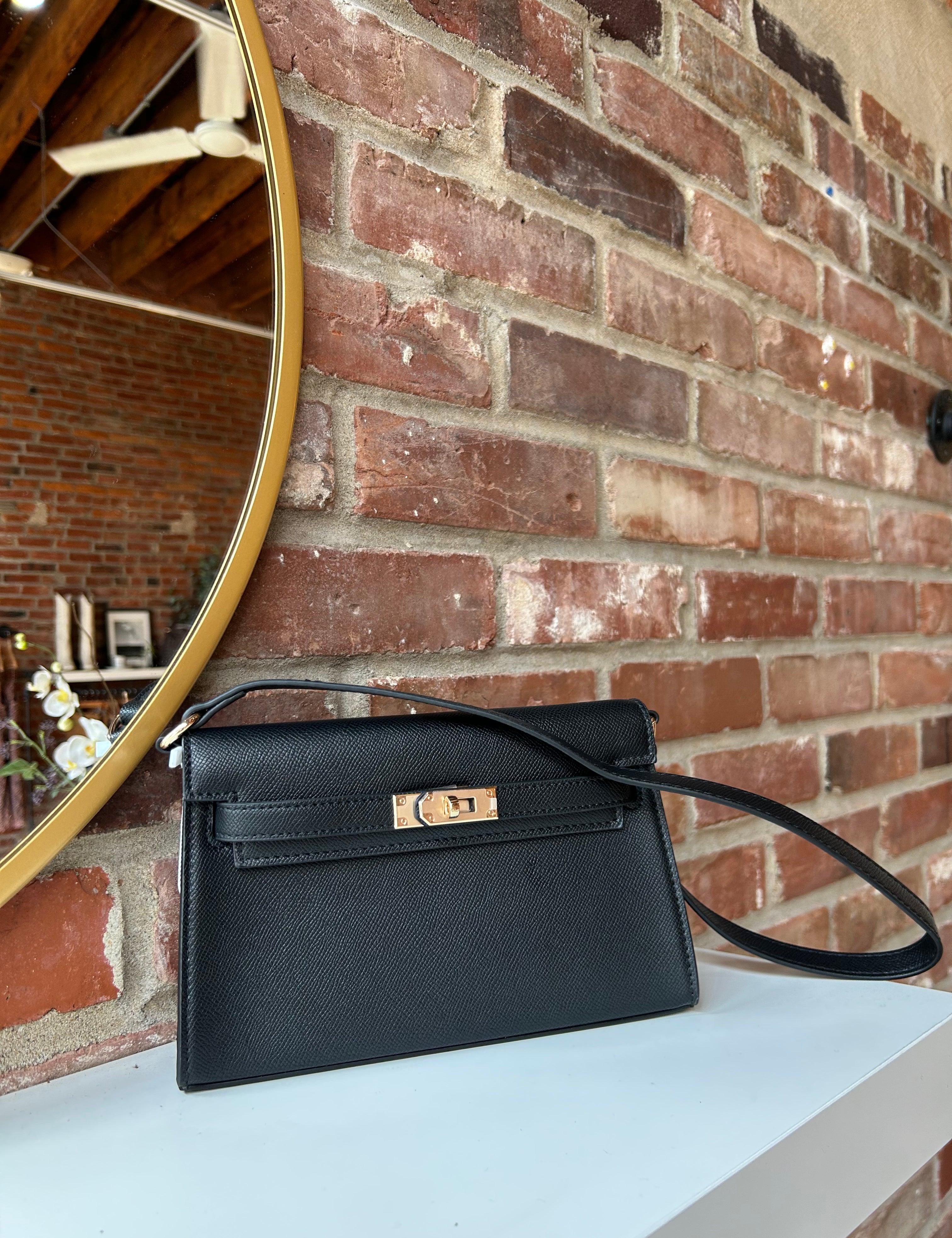 Black structured shoulder bag with elongated silhouette and gold clasp closure
