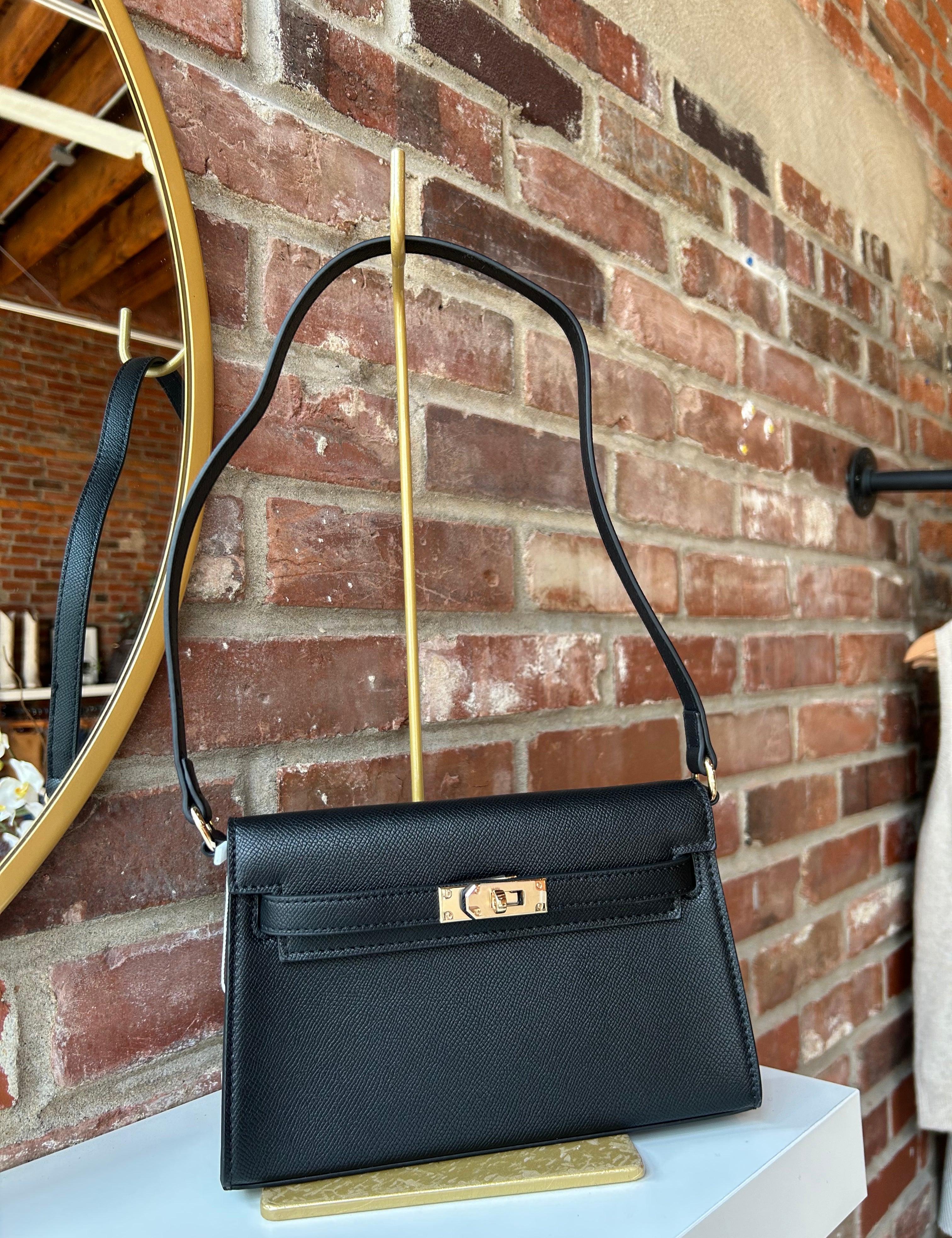 Black structured shoulder bag with elongated silhouette and gold clasp closure