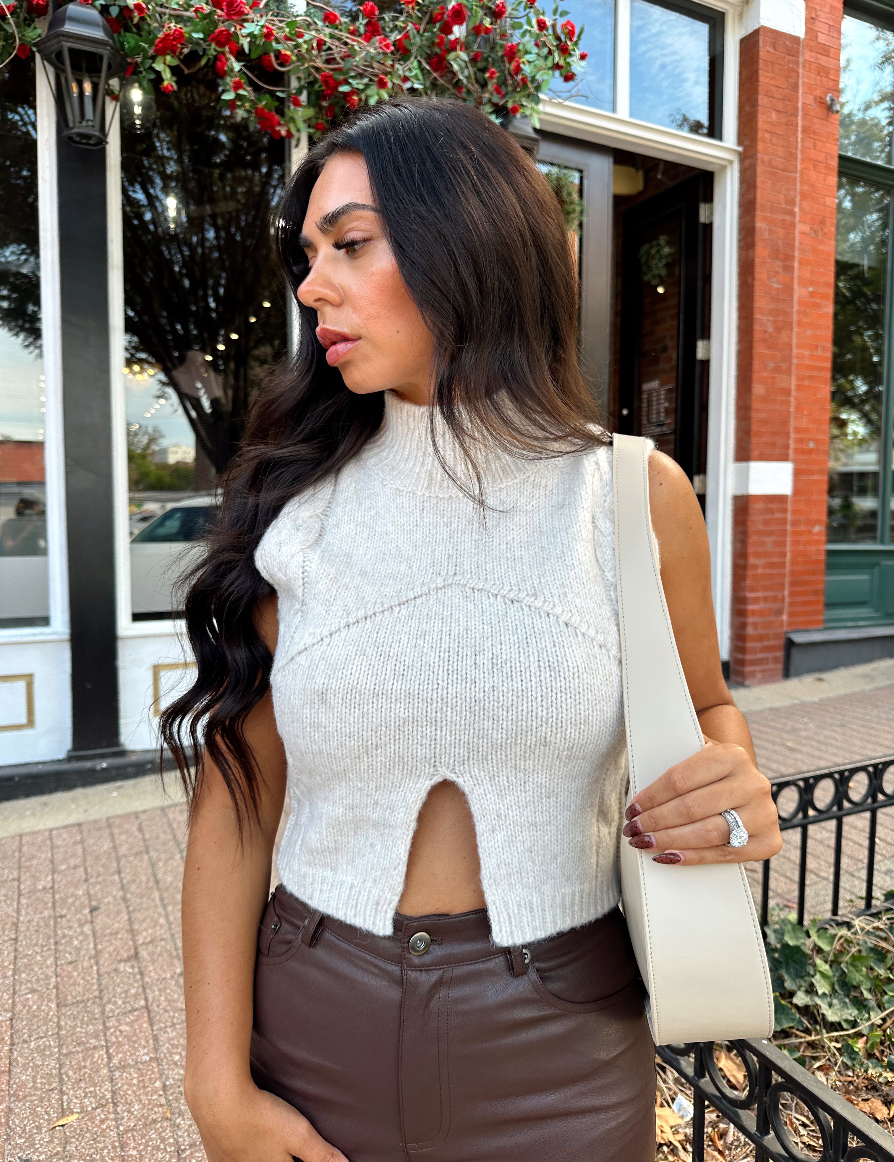 Woman wearing oatmeal knit sweater top with brown leather pant. 