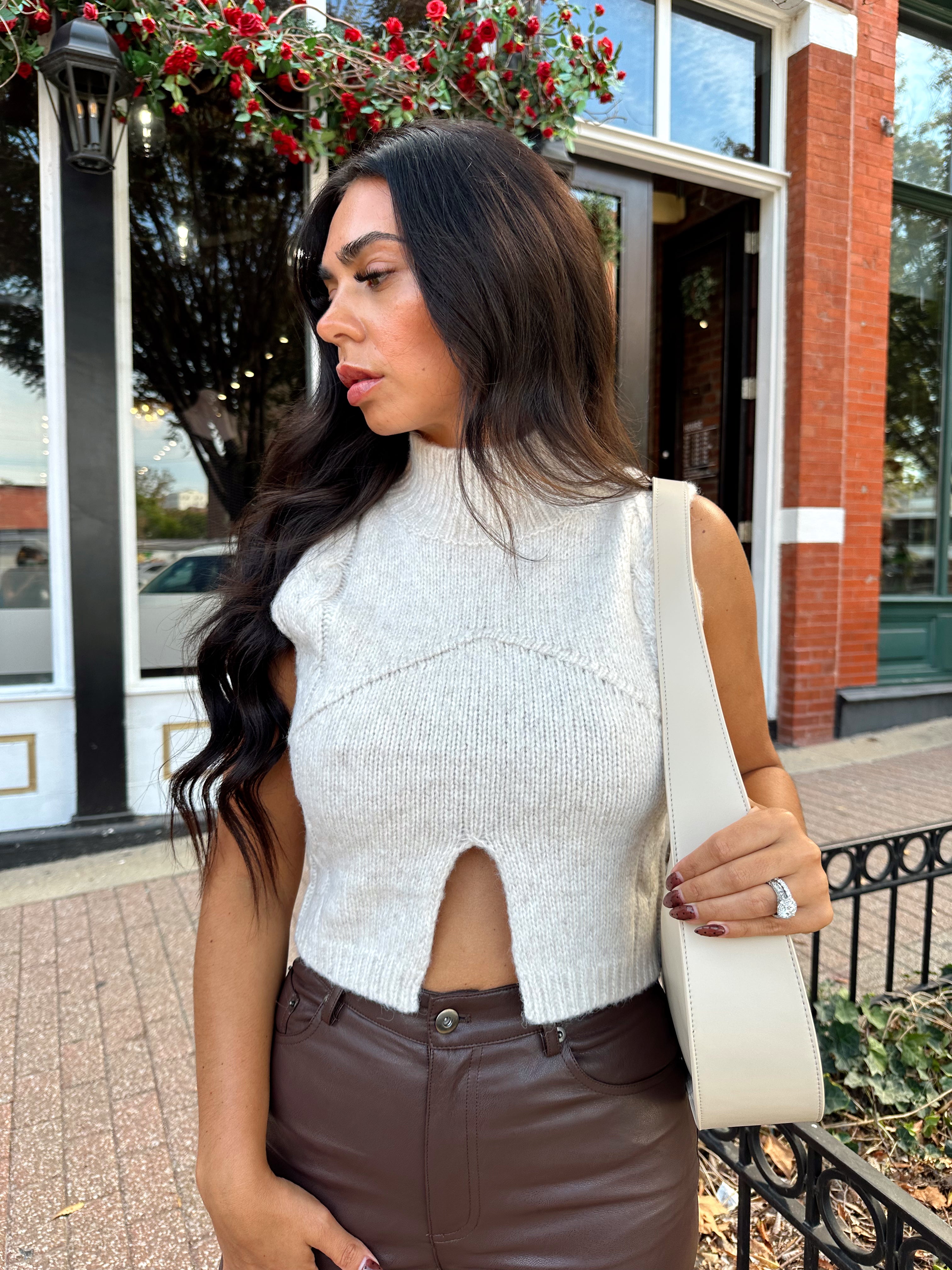 Woman wearing oatmeal knit sweater top with brown leather pant. 