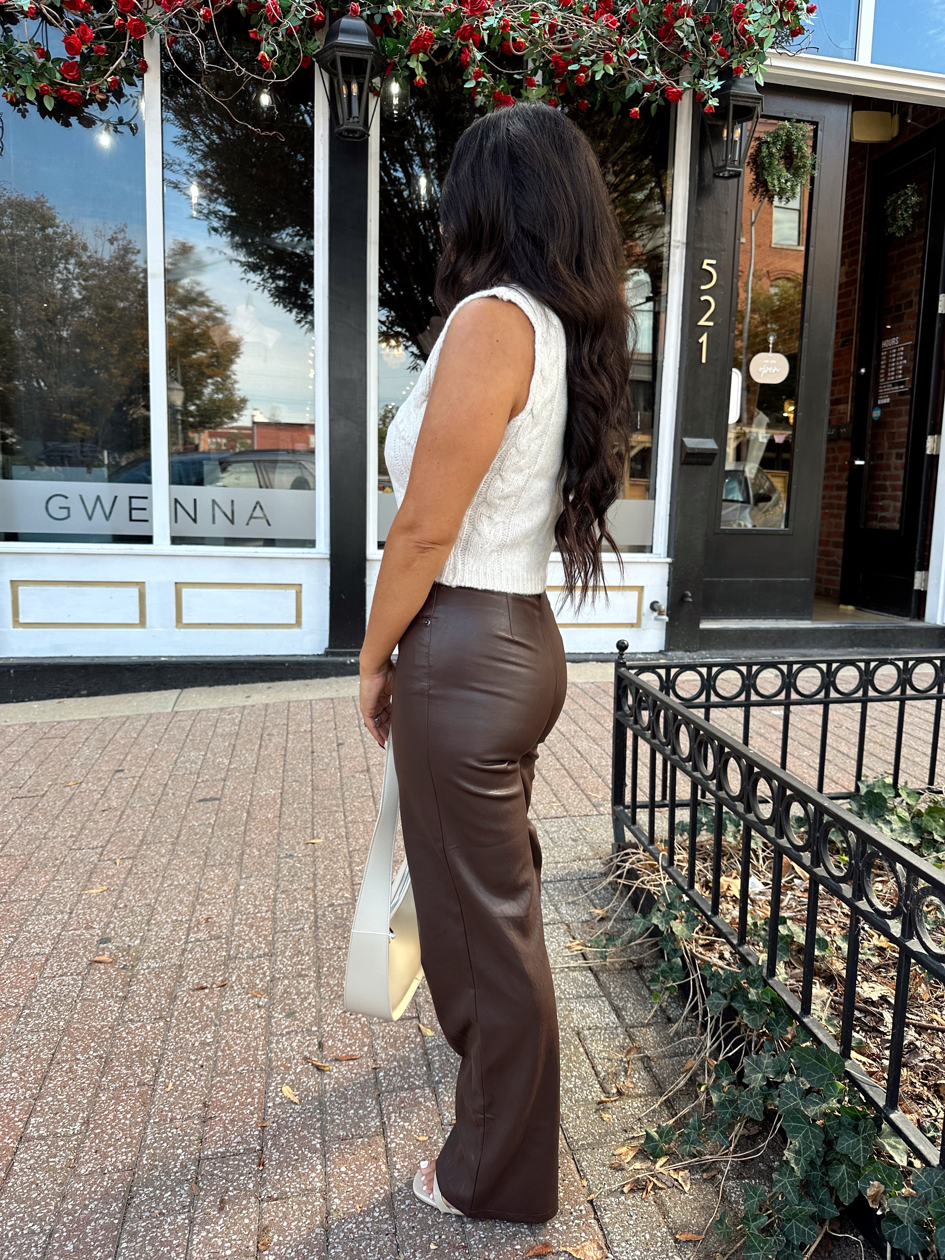 Woman wearing oatmeal knit sweater top with brown leather pant. 