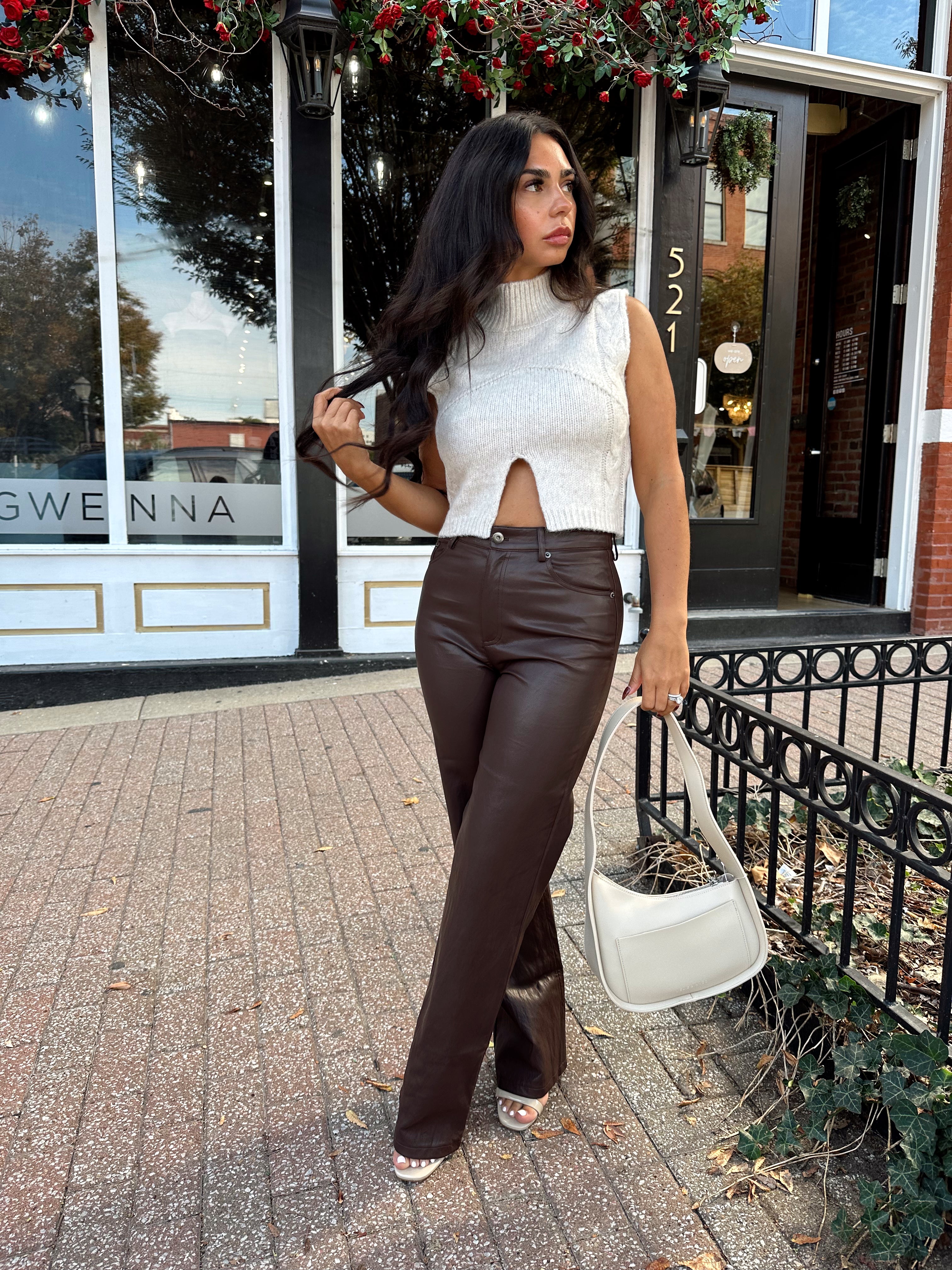 Woman wearing oatmeal knit sweater top with brown leather pant. 