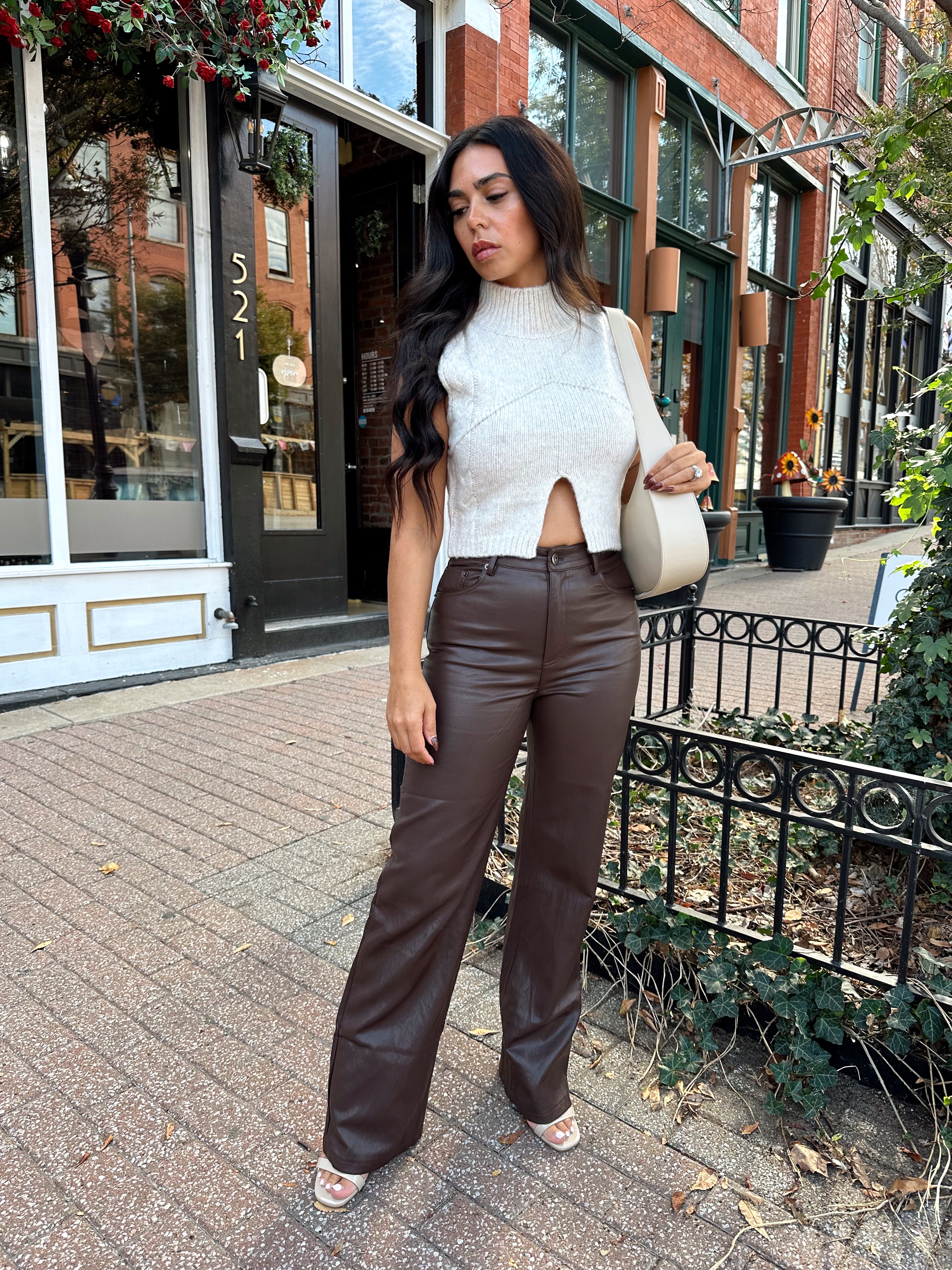 Woman wearing oatmeal knit sweater top with brown leather pant. 