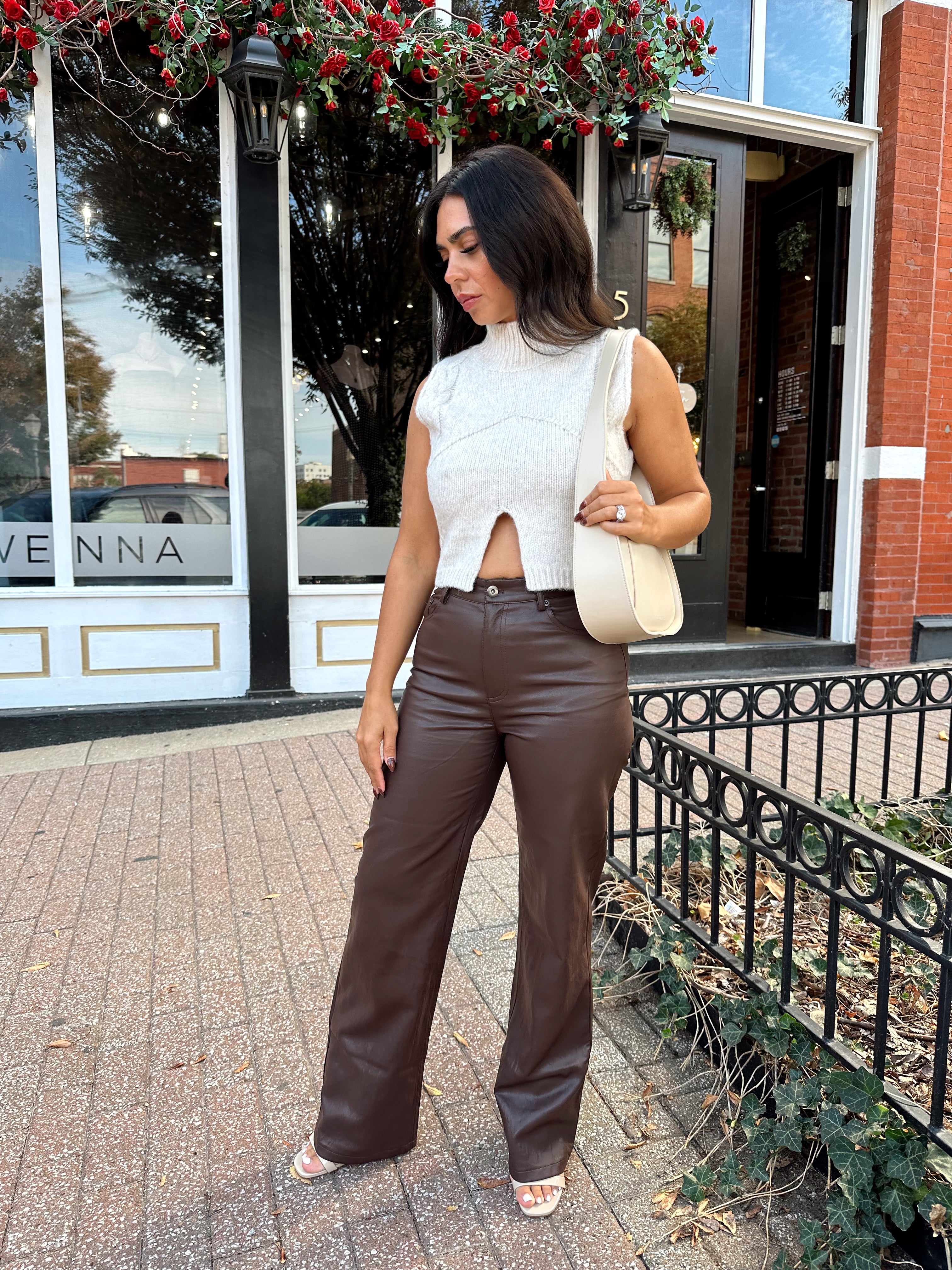 Woman wearing oatmeal knit sweater top with brown leather pant. 