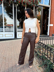 Woman wearing oatmeal knit sweater top with brown leather pant. 