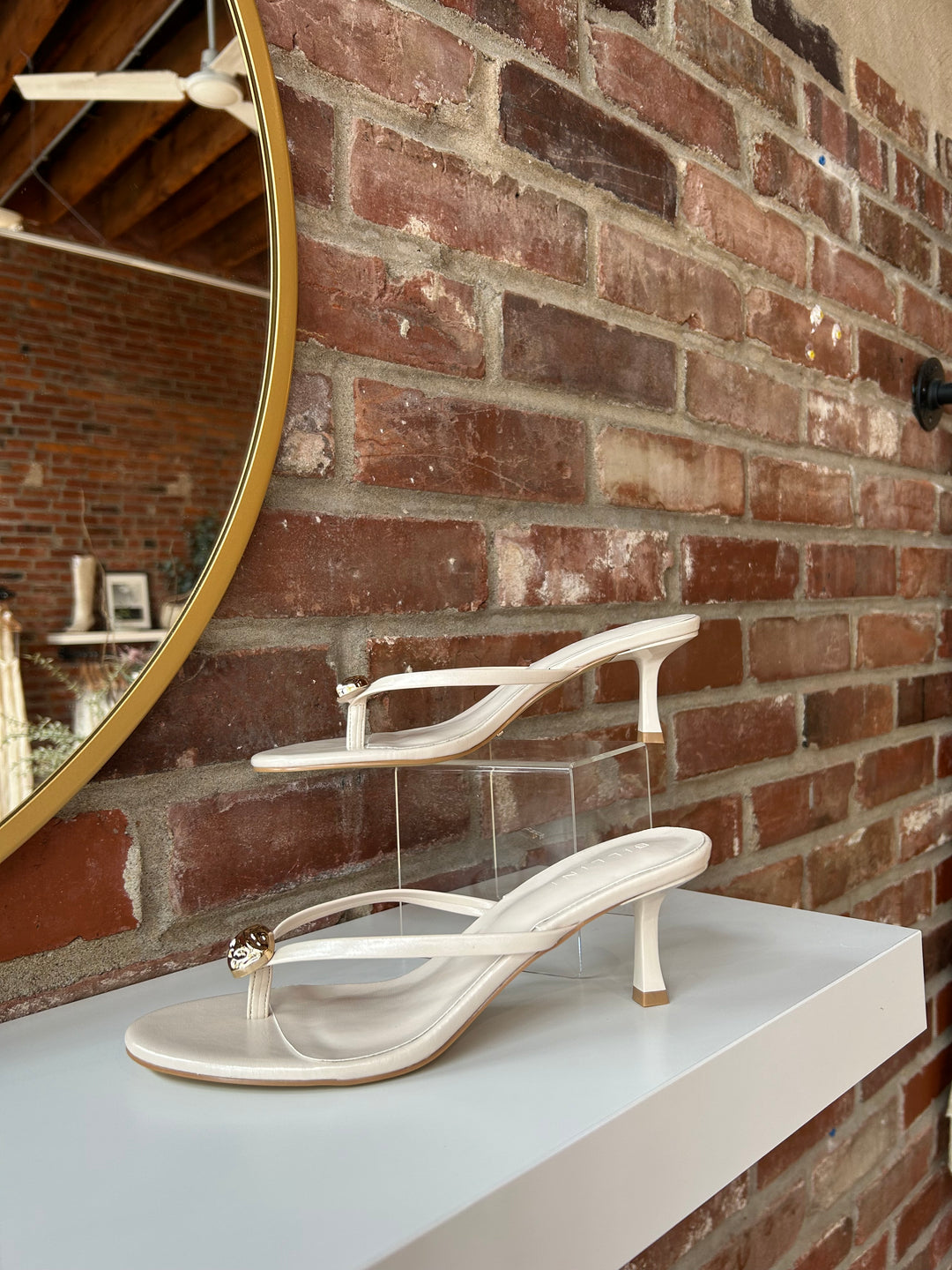 Cream colored flip flop kitten heel with a gold accent hardware detail. 