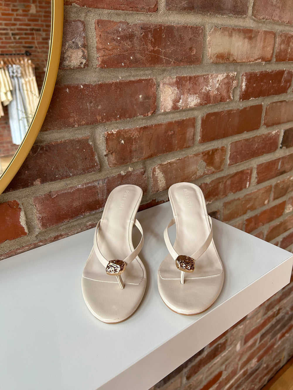 Cream colored flip flop kitten heel with a gold accent hardware detail. 
