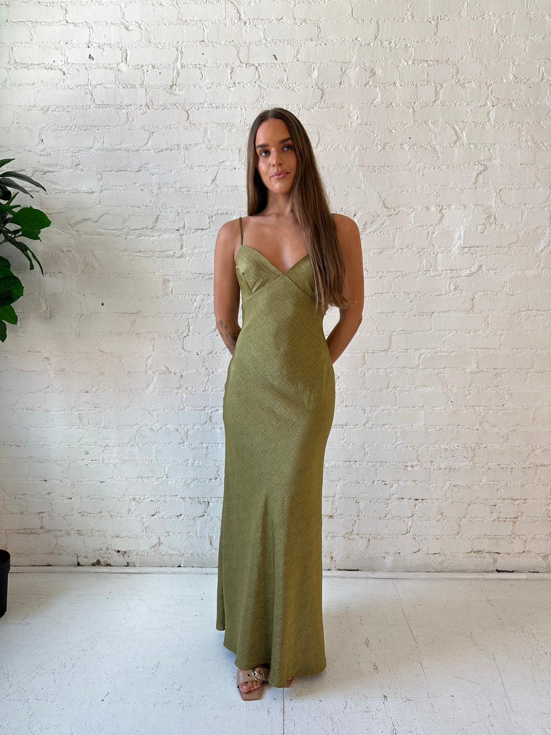 Woman wearing olive green textured maxi dress with v-neckline and adjustable spaghetti straps. 