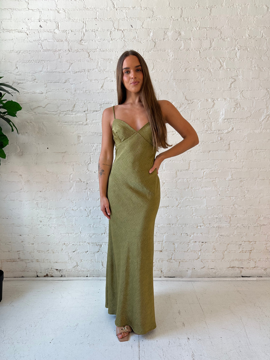 Woman wearing olive green textured maxi dress with v-neckline and adjustable spaghetti straps. 