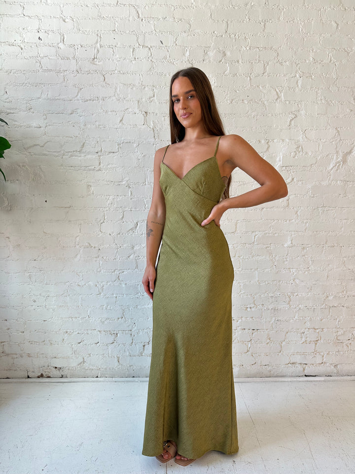 Woman wearing olive green textured maxi dress with v-neckline and adjustable spaghetti straps. 
