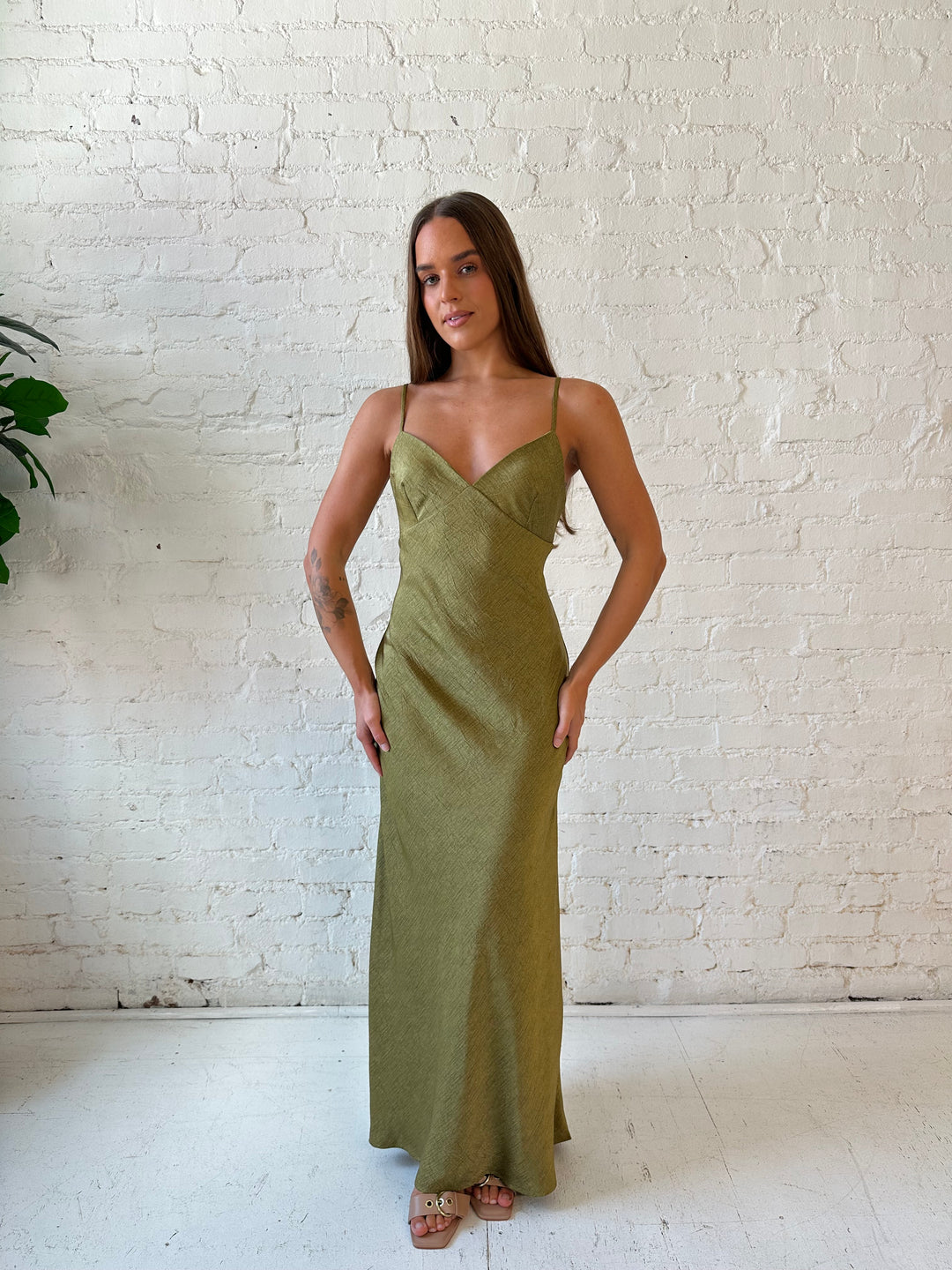 Woman wearing olive green textured maxi dress with v-neckline and adjustable spaghetti straps. 